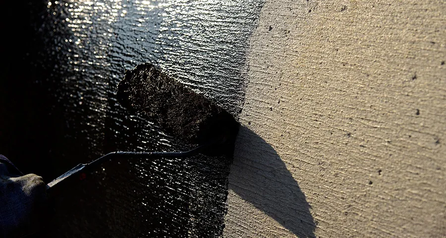 using a roller to apply Asphalt Primer on a roof 