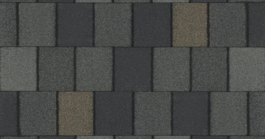 Close-up of a textured gray and black roof shingle pattern with vertical and horizontal rectangles.