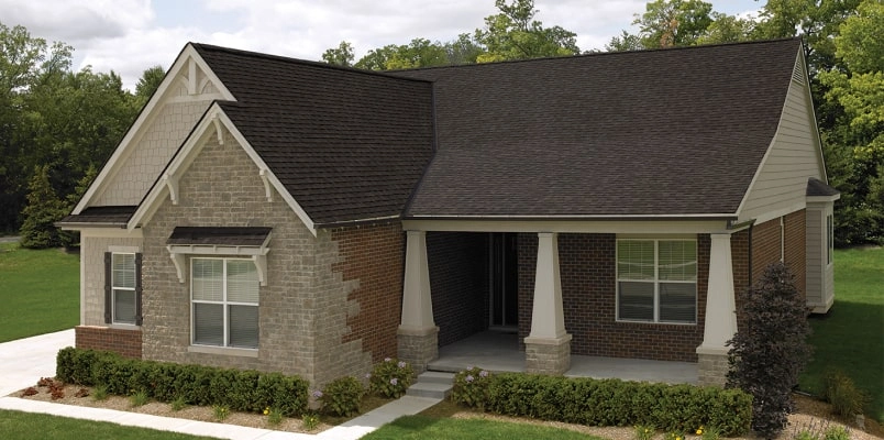 Front view of a modern house in Cambridge with a brick facade, dark shingle roof, and a small porch. Shrubs and a concrete path create an inviting entrance.