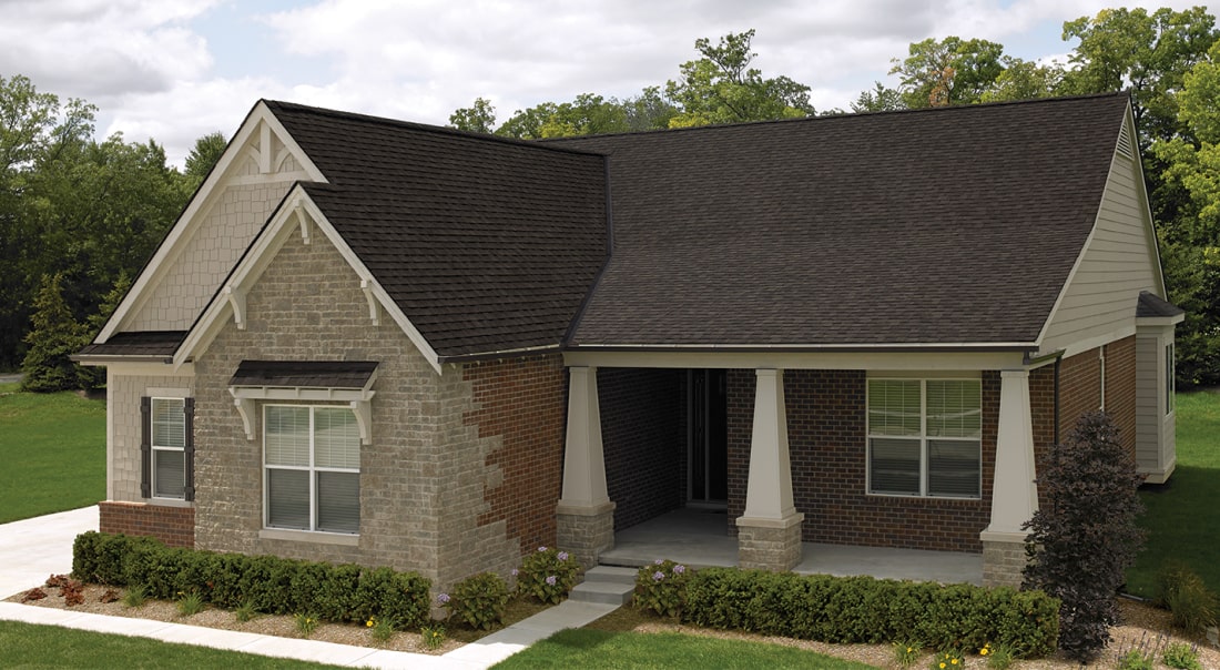 Front view of a modern house in Cambridge with a brick facade, dark shingle roof, and a small porch. Shrubs and a concrete path create an inviting entrance.