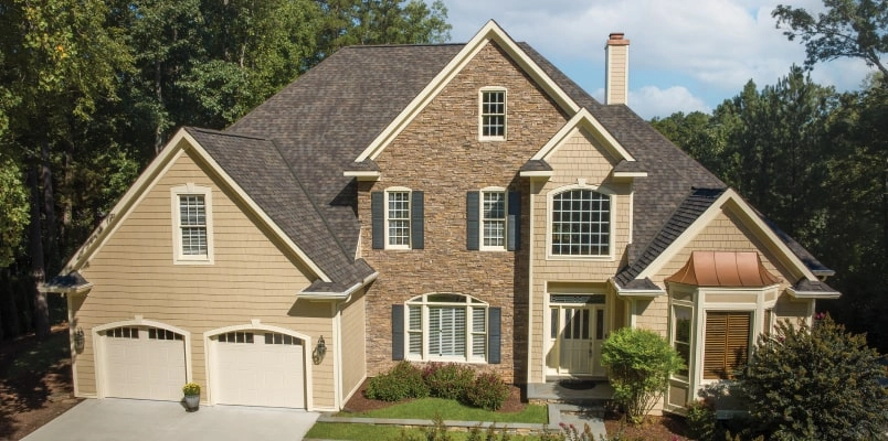 This two-story brick house showcases a touch of dynasty with its elegant white siding, black shutters, and shingled roof. The striking red front door and bay window invite you into a beautifully landscaped front yard.