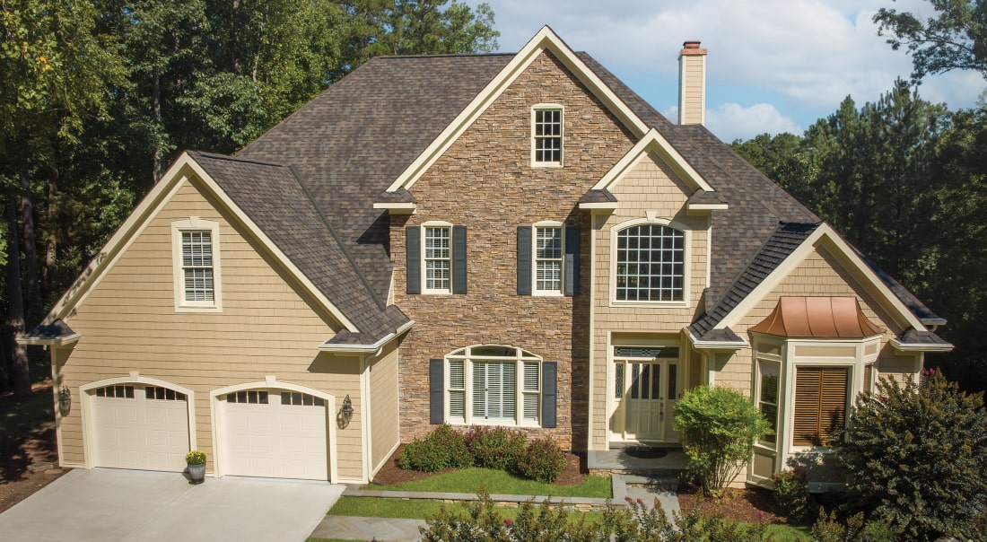 This two-story brick house showcases a touch of dynasty with its elegant white siding, black shutters, and shingled roof. The striking red front door and bay window invite you into a beautifully landscaped front yard.