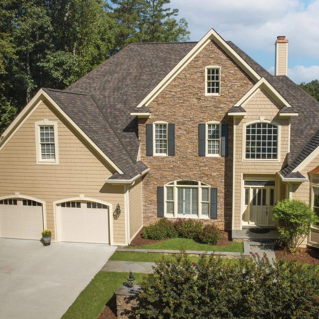 This two-story brick house showcases a touch of dynasty with its elegant white siding, black shutters, and shingled roof. The striking red front door and bay window invite you into a beautifully landscaped front yard.