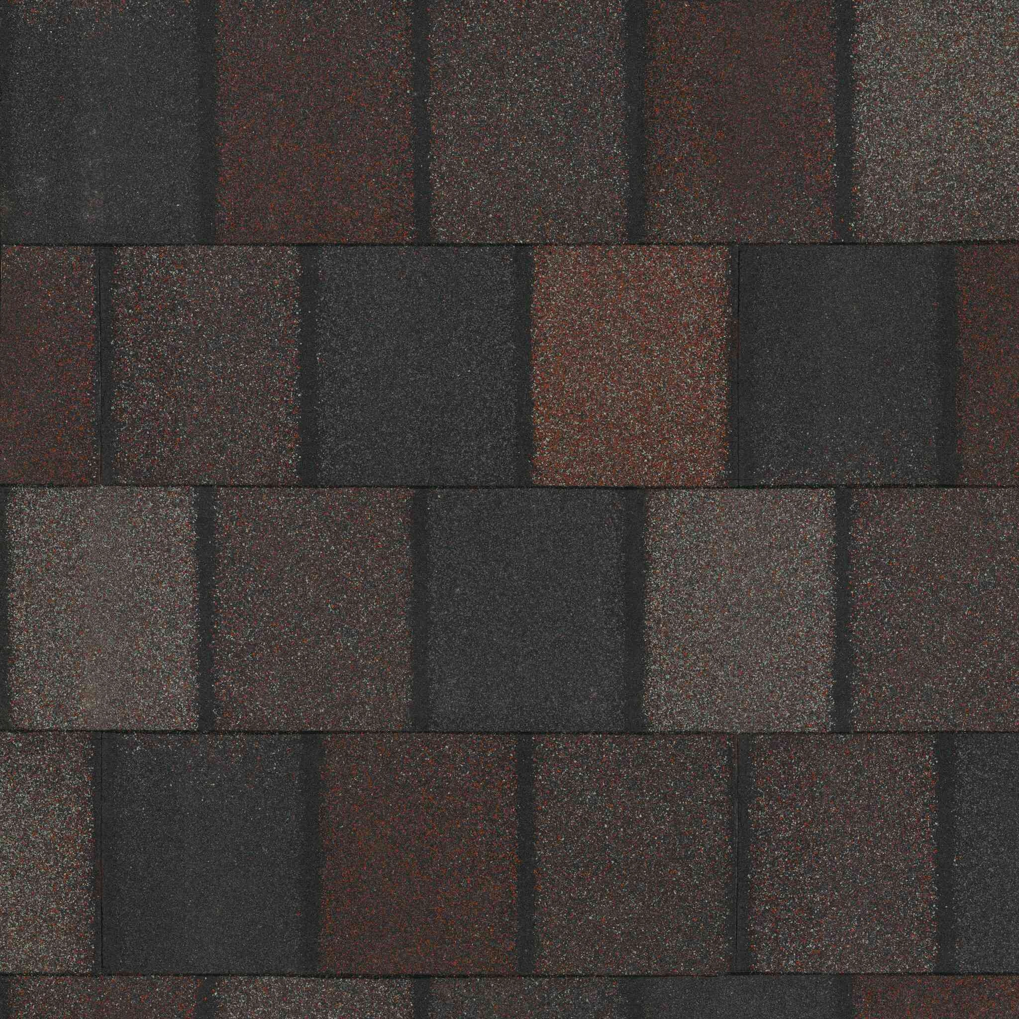 Close-up of an asphalt shingle roof with alternating dark and muted red-brown tiles in a rectangular pattern, reminiscent of Crowne Slate.