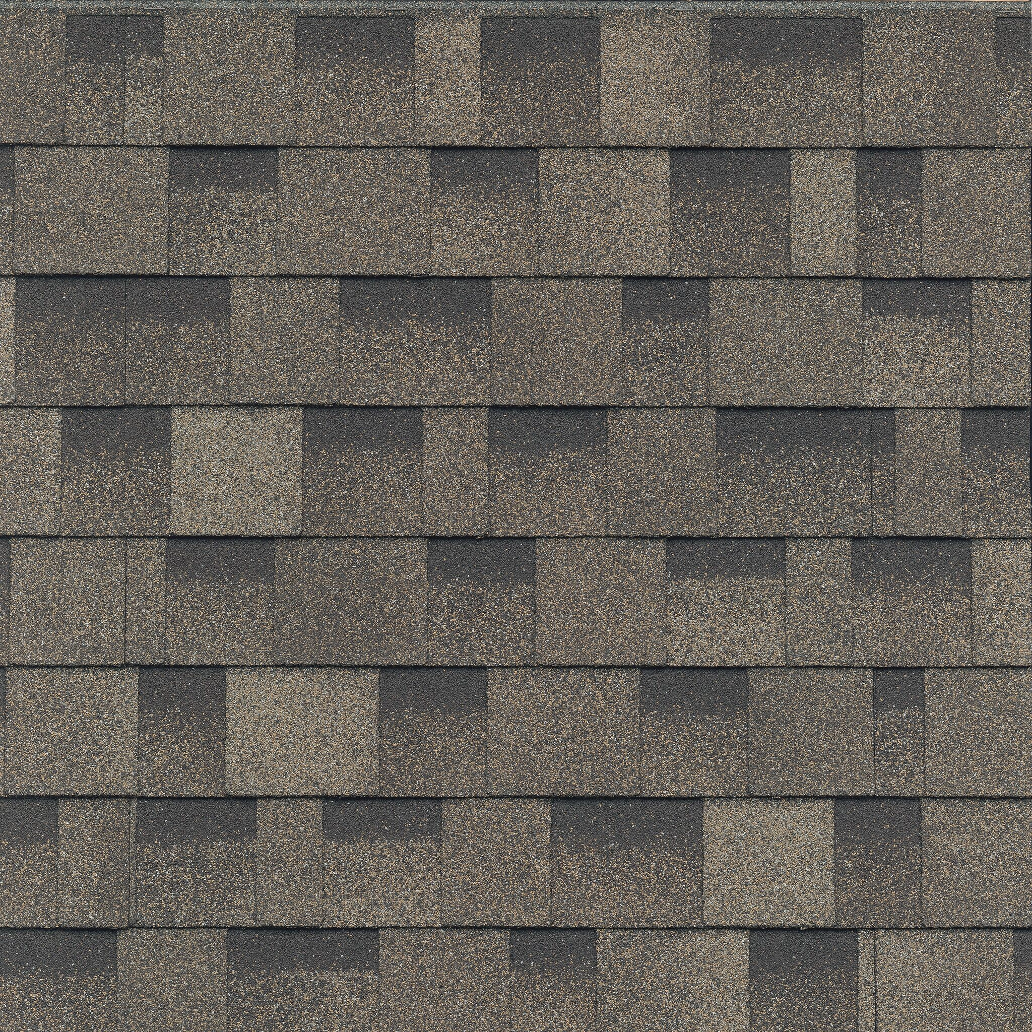 Close-up of a roof featuring Cambridge Cool Colors with overlapping asphalt shingles in shades of gray and brown, arranged in a staggered pattern reminiscent of a sand dune.