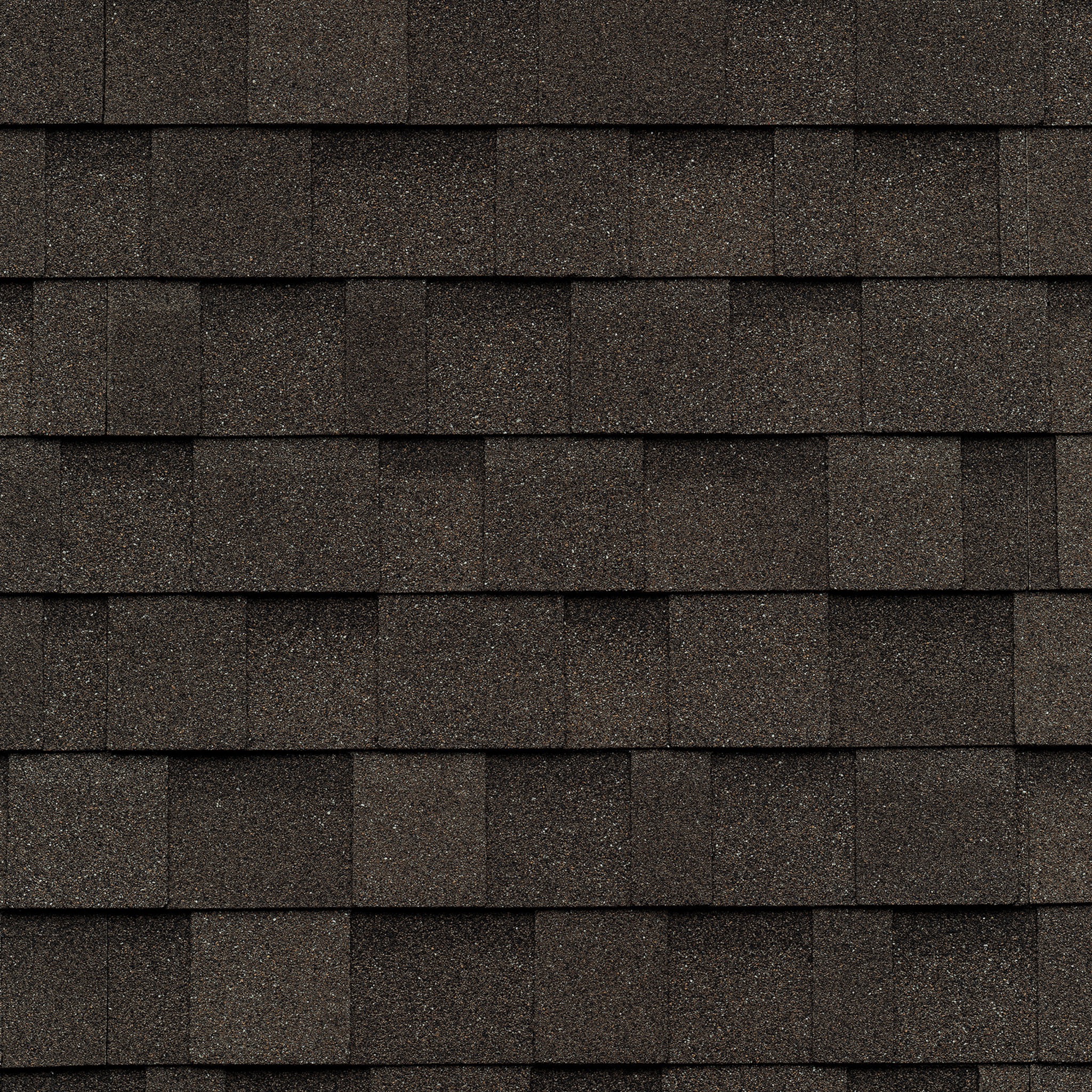 Close-up of overlapping dark gray asphalt roof shingles, reminiscent of the natural hues found in driftwood, arranged in a uniform pattern.