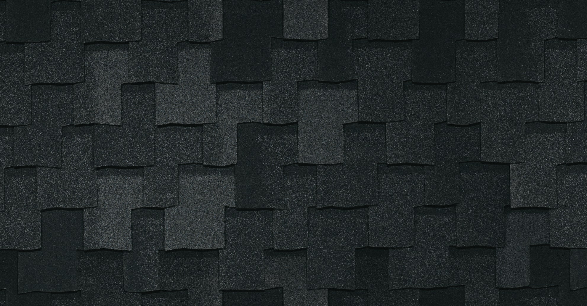 Armourshake Shadow Black roofing shingles are elegantly arranged in a layered pattern on a roof, offering a striking contrast with their dark green asphalt hue.