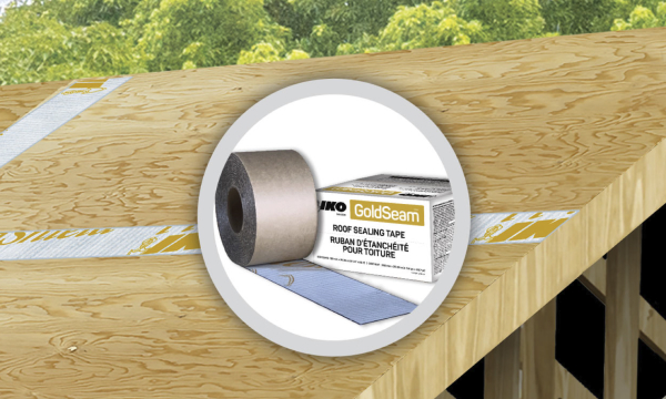 A roll of Gold Seam™ black and white tape partially unrolled on plywood flooring.