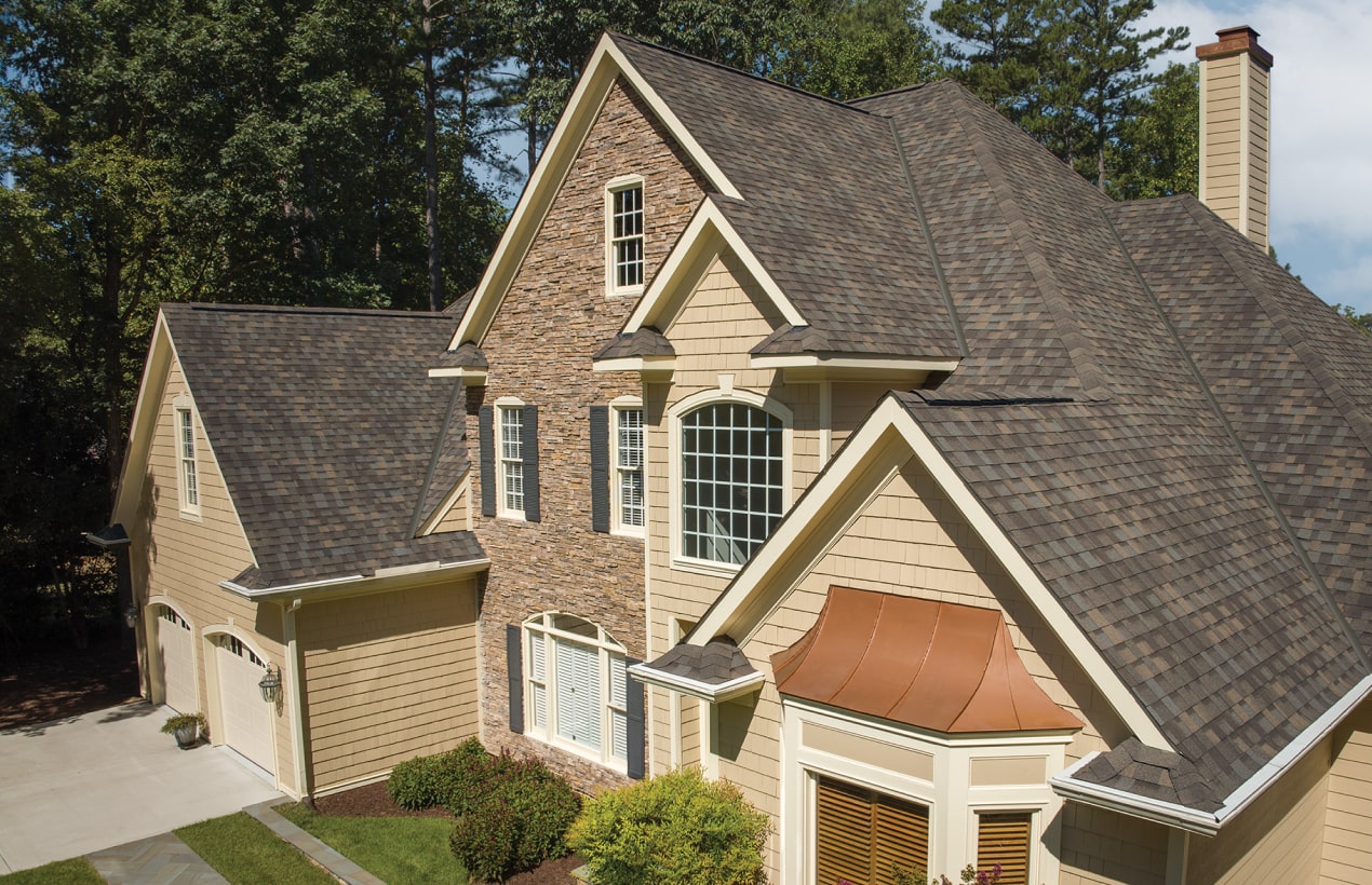 A Nordic™ chalet-style building with steep gabled roofs, wood accents, and exterior staircases is beautifully surrounded by lush greenery.