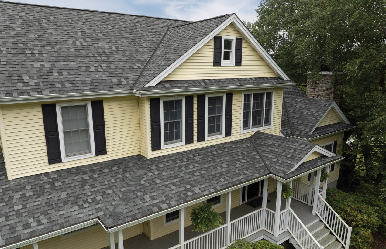 A Nordic™ chalet-style building with steep gabled roofs, wood accents, and exterior staircases is beautifully surrounded by lush greenery.