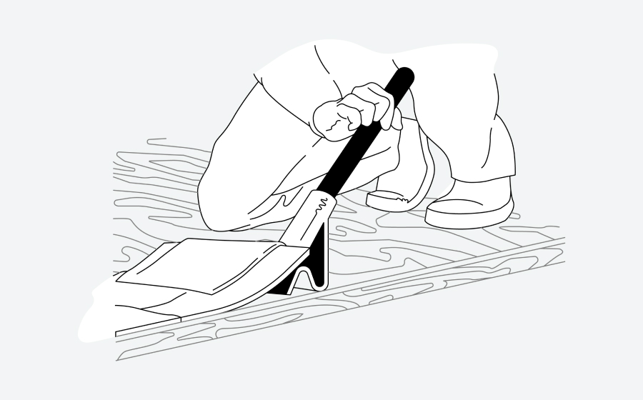 Person kneeling on a floor, using a tool for smoothing or leveling flooring material.