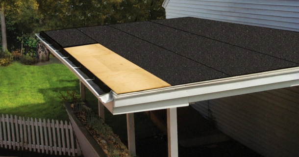 Close-up of a Roof-Fast installation shows exposed wood with partially installed black asphalt shingles capping the structure, elegantly overhanging the crisp white gutters for a modern finish.