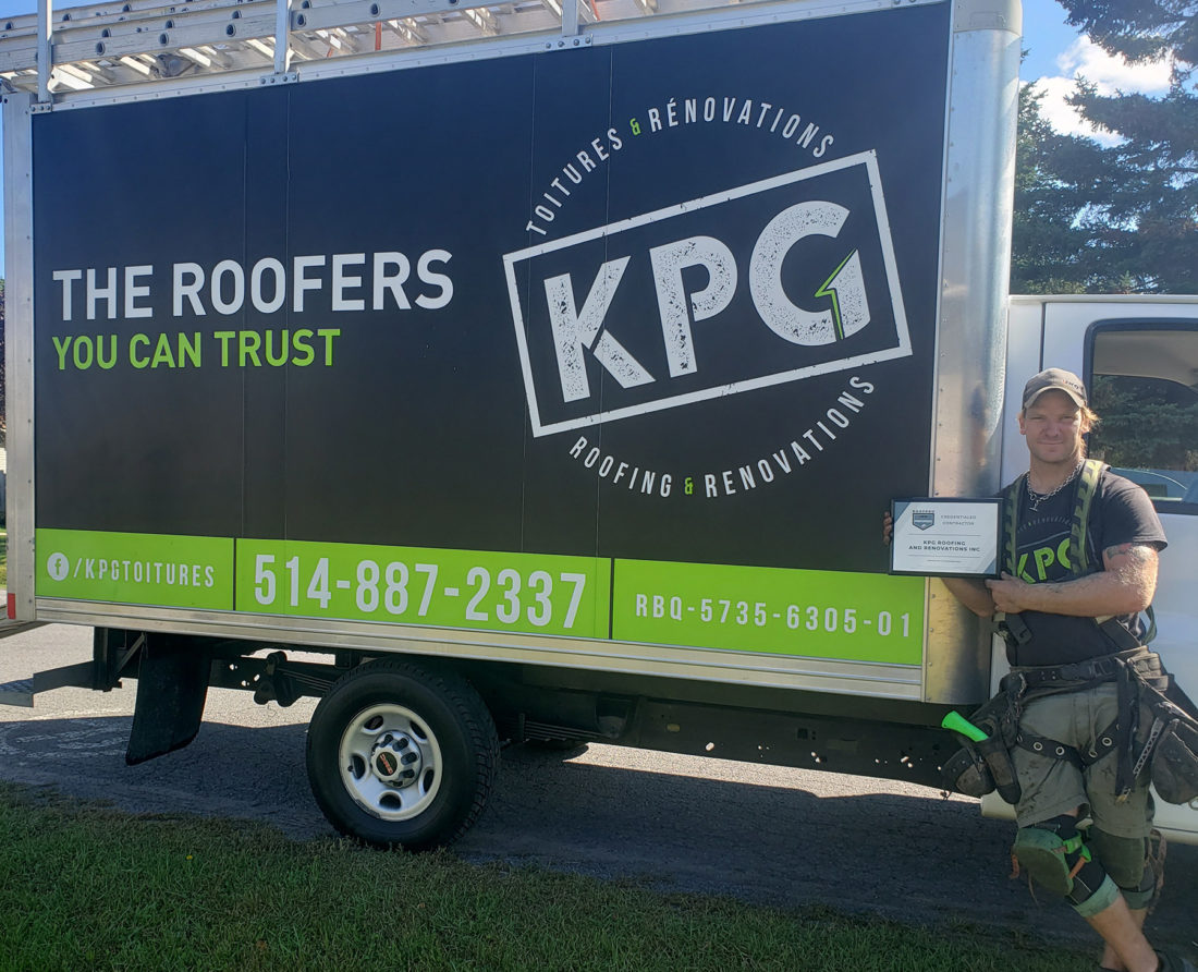 A person stands next to a truck with KPG roofing and renovations branding, holding a certificate.