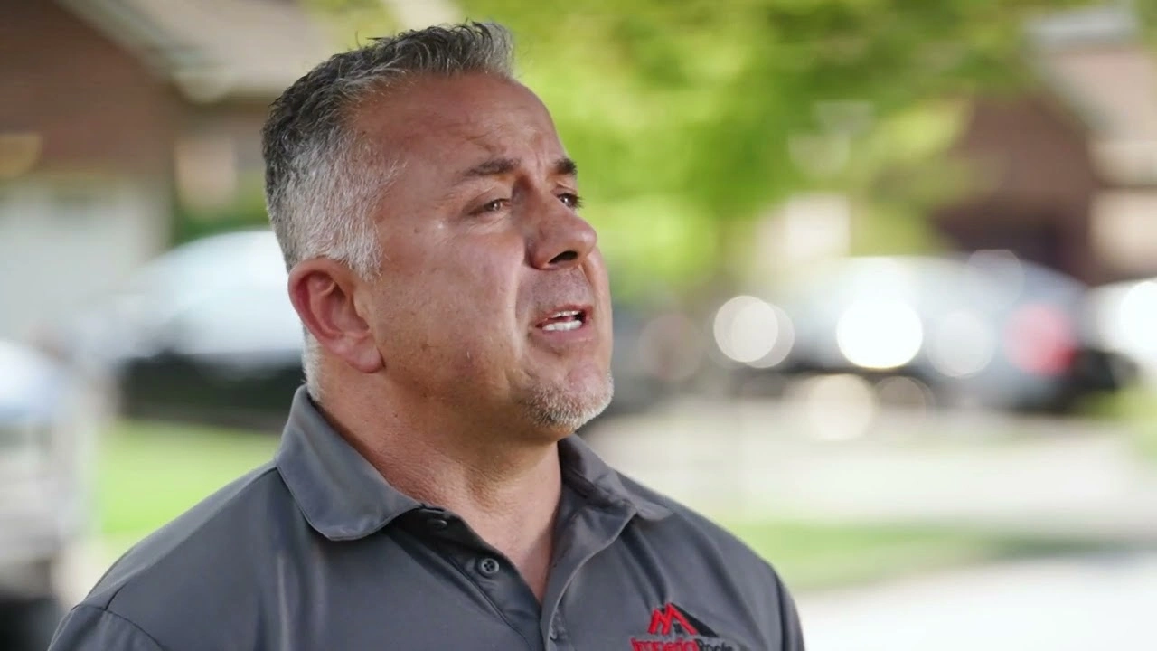 A man with short gray hair wearing a gray polo shirt stands outdoors in a suburban area, subtly showcasing the elegance of Imperial Accessories.