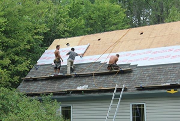 roofers installing underlyment and roofing shingles